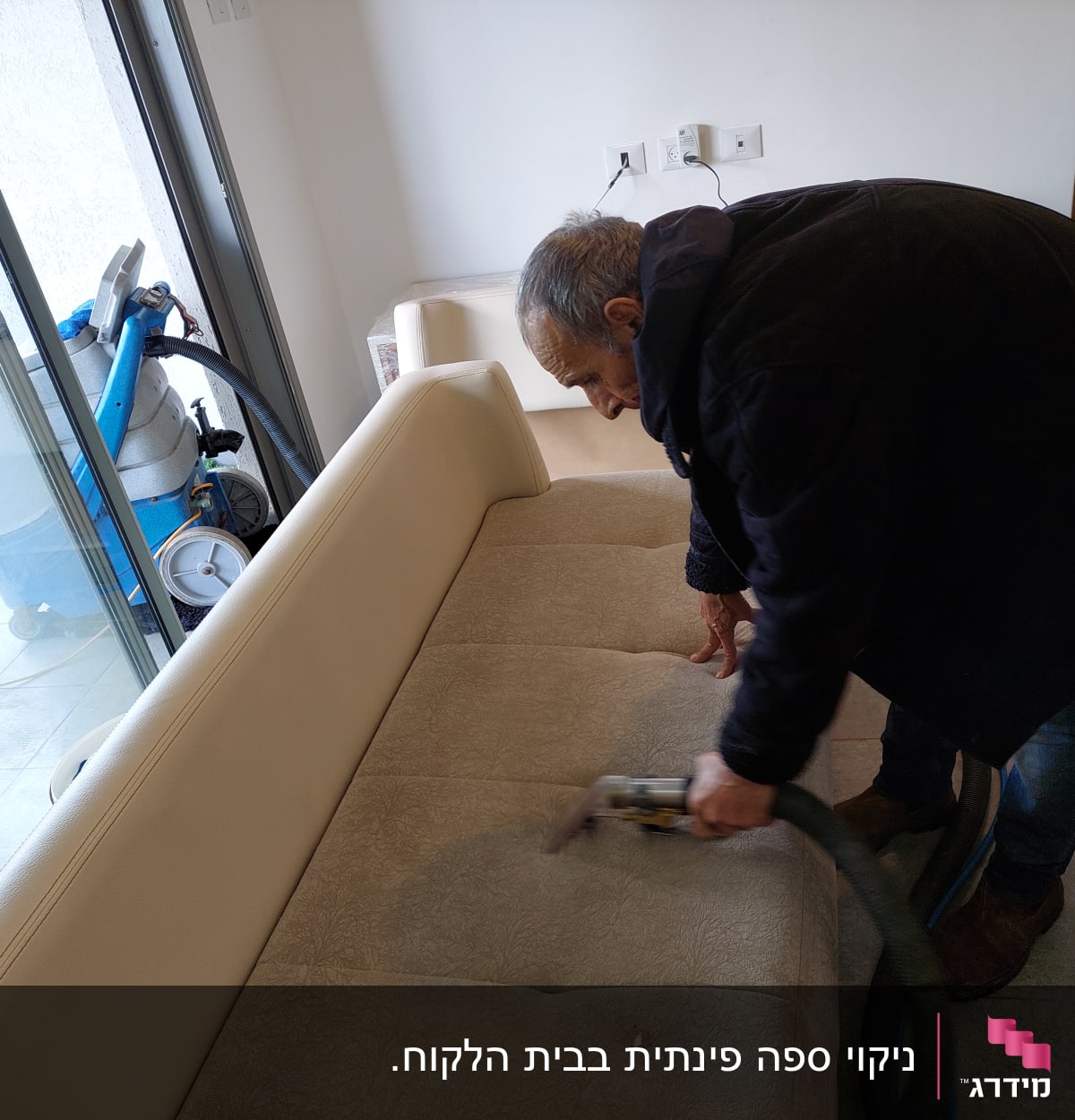 אדם מנקה ספה עם מכשיר ניקוי חשמלי